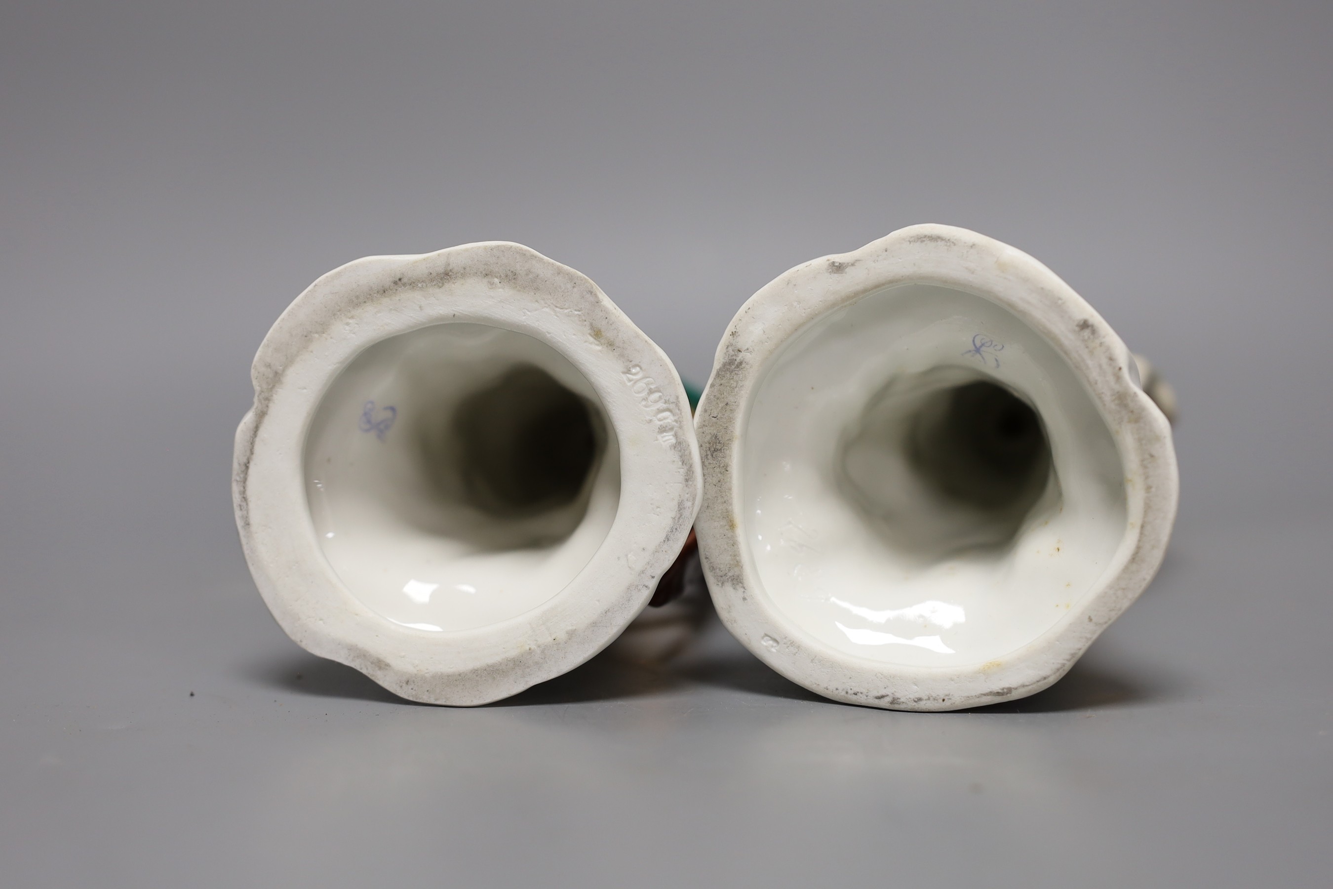A pair of Continental porcelain perching parrots, 25cm tall